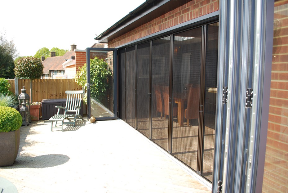 Insect screens across a wide exterior opening beside folded glass doors